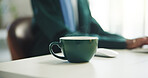 Cup, person and coffee on desk in office for relax, calm or peaceful morning at creative career. Professional, mug and magazine editor with warm beverage or drink at startup business in workplace.