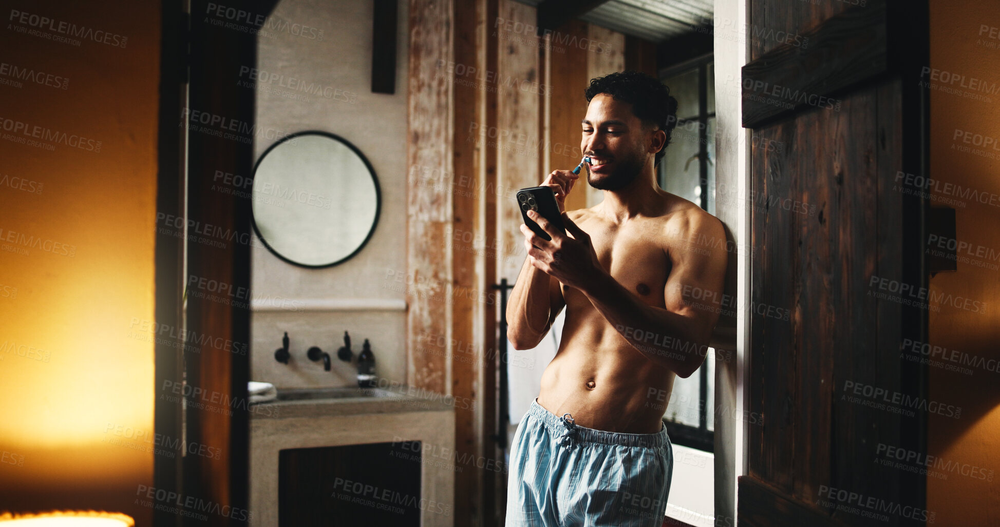 Buy stock photo Phone, brushing teeth and man in home for dental wellness, hygiene and morning news. Mobile, cleaning mouth and shirtless person by bathroom doorway for oral care, health and reading message online