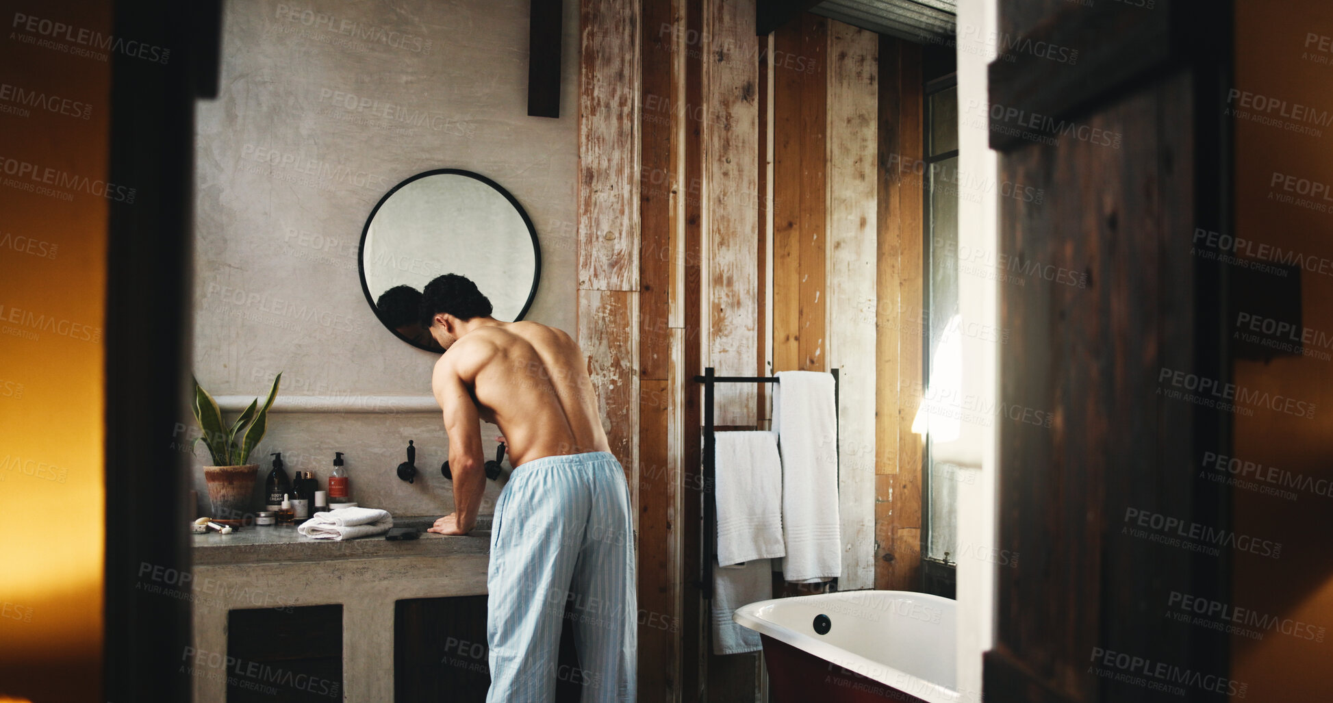 Buy stock photo Back, basin and doorway with shirtless man in bathroom of hotel room for hygiene or morning routine. Entrance, start and wake up with person at sink for accommodation, break or hospitality as guest