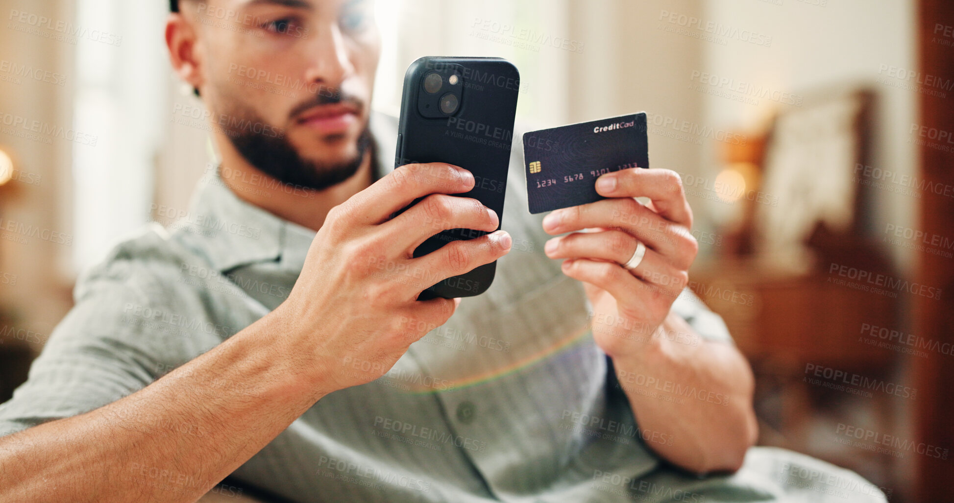 Buy stock photo Credit card, purchase or man on sofa with phone, online banking or payment in eft transaction. Serious, easy transfer or male person at house with tech, remote or debit details for cashless service.