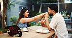Happy, couple and holding hands in restaurant, kiss and bonding on anniversary and date with partner. Outdoor, man and affection for woman on valentines day, bouquet or roses for celebration and love