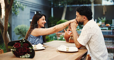 Buy stock photo Happy, couple and holding hands in restaurant, kiss and bonding on anniversary and date with partner. Outdoor, man and affection for woman on valentines day, bouquet or roses for celebration and love