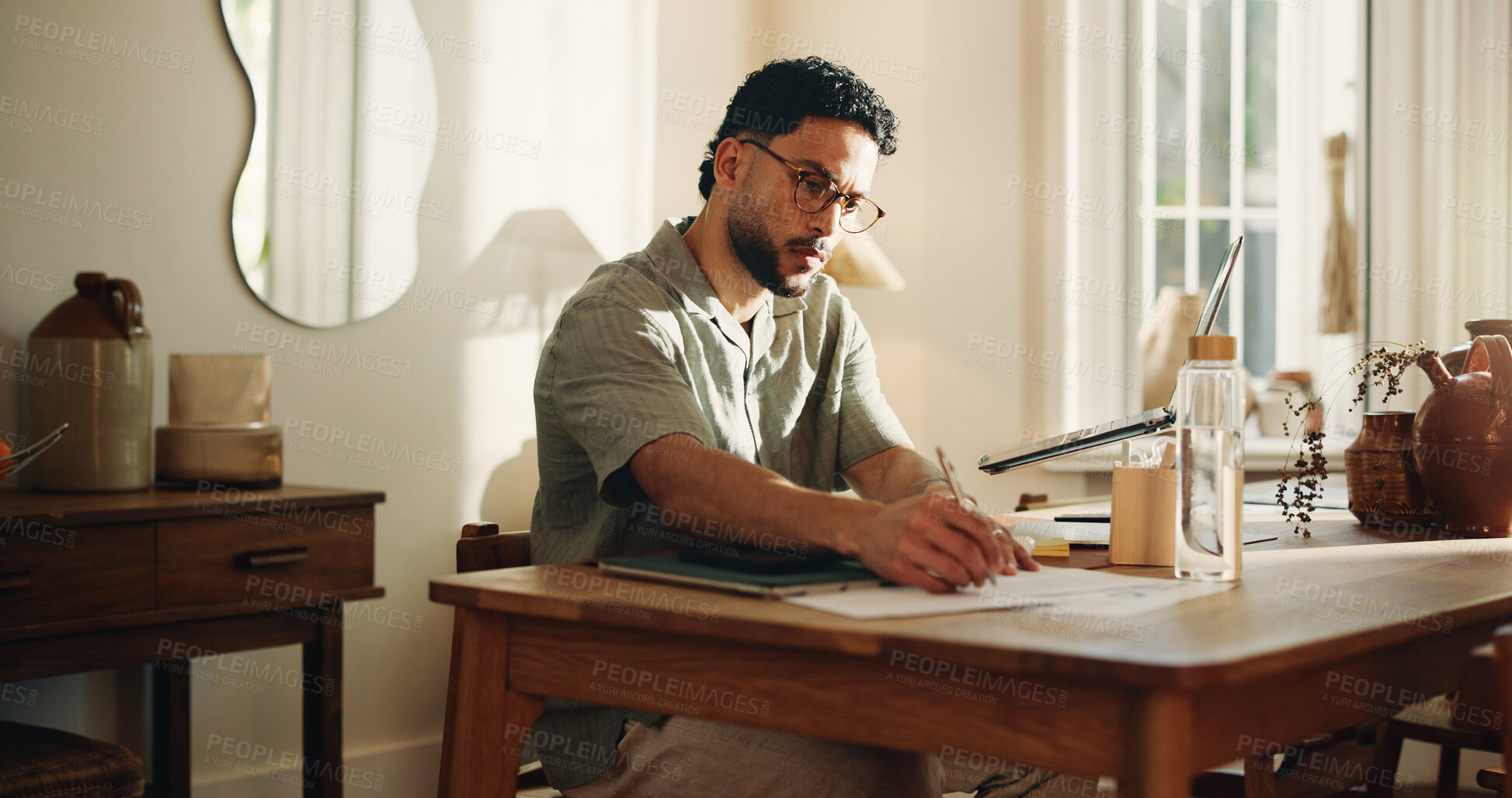 Buy stock photo Documents, remote work and writing with man in home office for journalism or publication. Paperwork, pen and planning with freelance journalist at desk in study of apartment for article research
