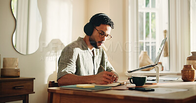 Buy stock photo Headphones, remote work and writing with man in home office for journalism or publication. Music, notebook and pen with freelance journalist at desk in study of apartment for article research