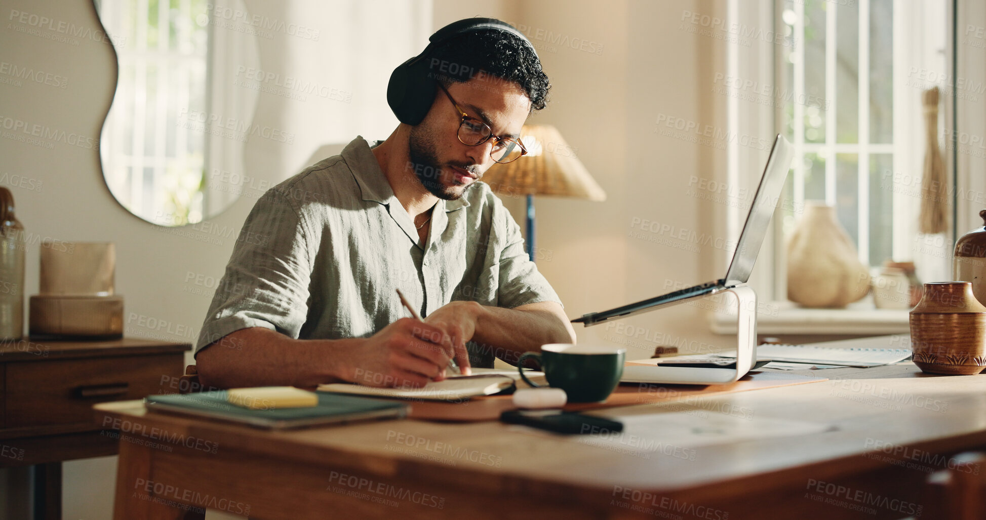 Buy stock photo Man, journalist and writing with laptop in home for online story, article or remote work. Male person, freelancer or taking notes with book, headphones or computer for journalism or schedule diary