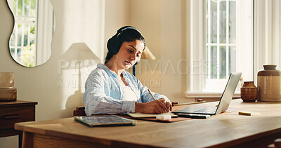 Buy stock photo Headphones, remote work and writing with woman in home office for journalism or publication. Notes, pen and planning with freelance journalist at desk in study of apartment for article research