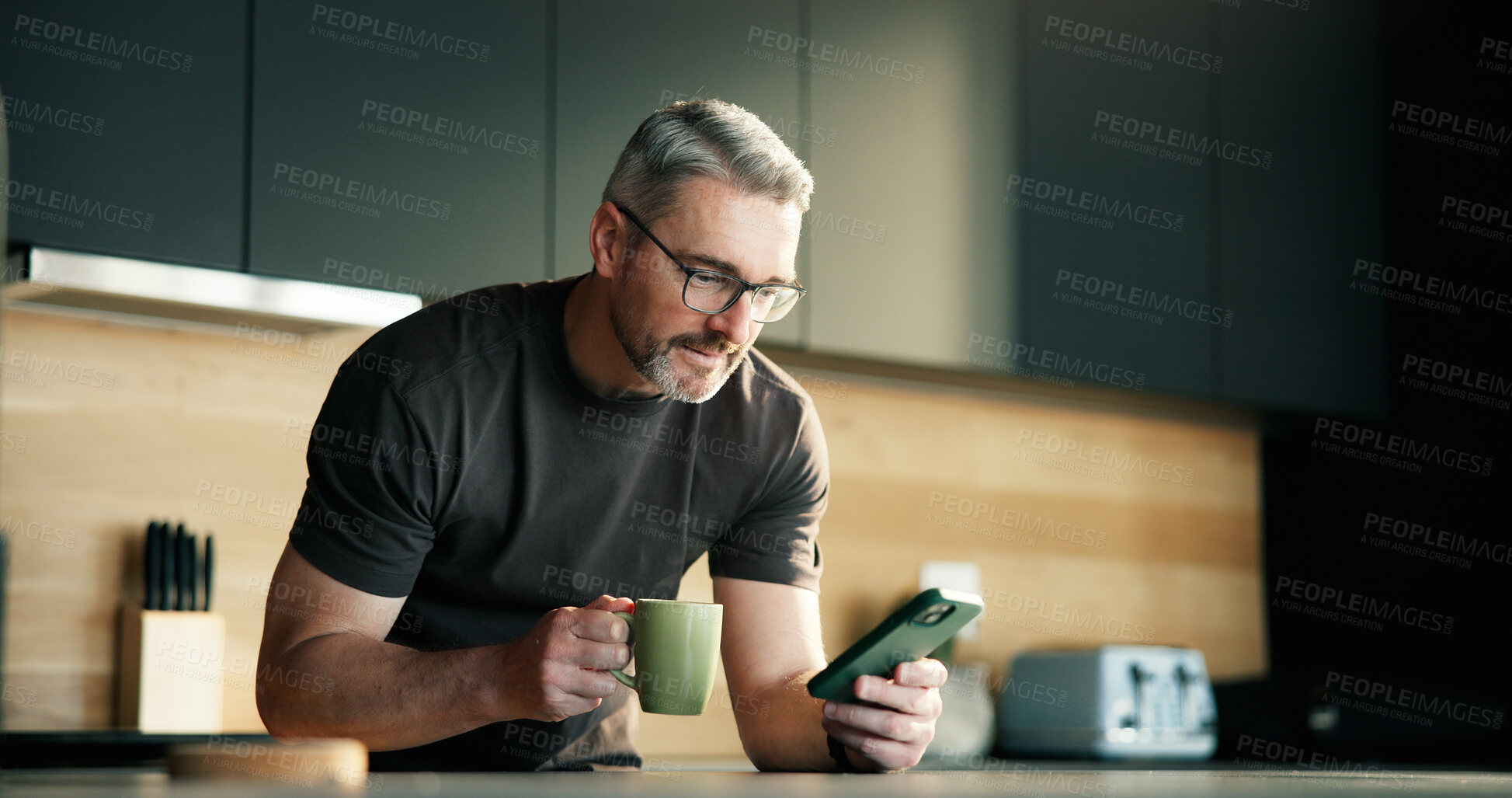 Buy stock photo Man, coffee and scroll in kitchen with phone for social media notification, text message and news feed. Mature person, hot drink and browse with tech in home for online chat, reading article or blog.