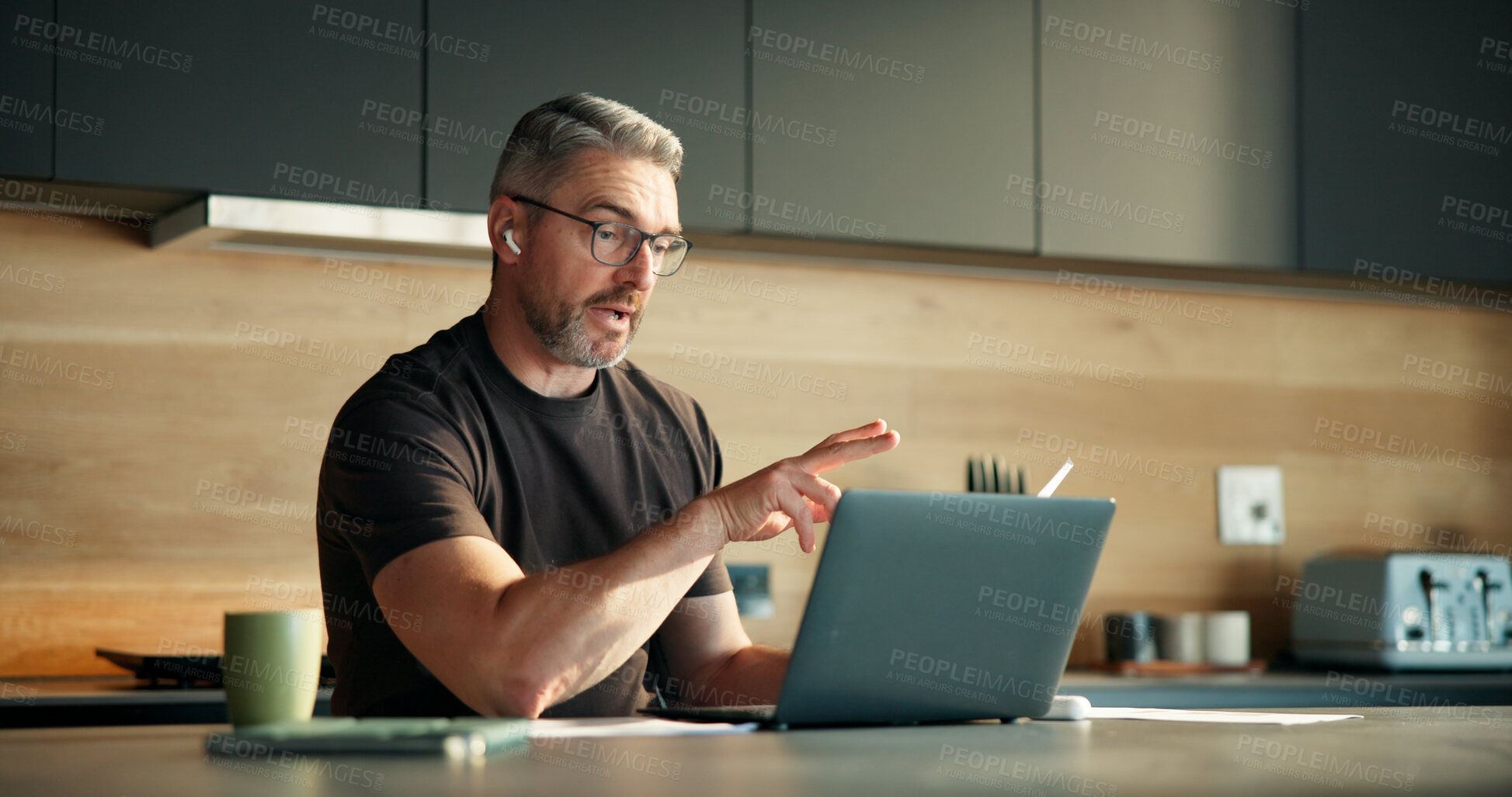 Buy stock photo Explain, laptop and video call with man in kitchen of home for feedback, planning or remote work. Computer, conversation and serious with mature freelancer in apartment for virtual meeting or webinar