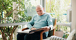 Senior man, reading book and relax in living room with story, literature and novel in retirement at house. Elderly person, information and knowledge with language, fiction or learning in nursing home