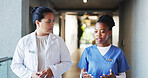 Doctor, nurse and walking with discussion in clinic for medical opinion, treatment plan and advice. Women, healthcare team and talking in hallway with results feedback, hospital management and update