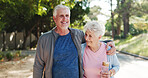 Park, happy and senior couple hug with water bottle for wellness, health and fitness together. Outdoor, morning and elderly man and woman embrace for active workout, exercise and walking for bonding