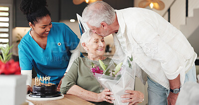 Buy stock photo Senior couple, nurse and kiss with flowers for birthday or anniversary in retirement home together. Elderly, man and woman with caregiver, cake or floral bouquet for love, romance or celebration