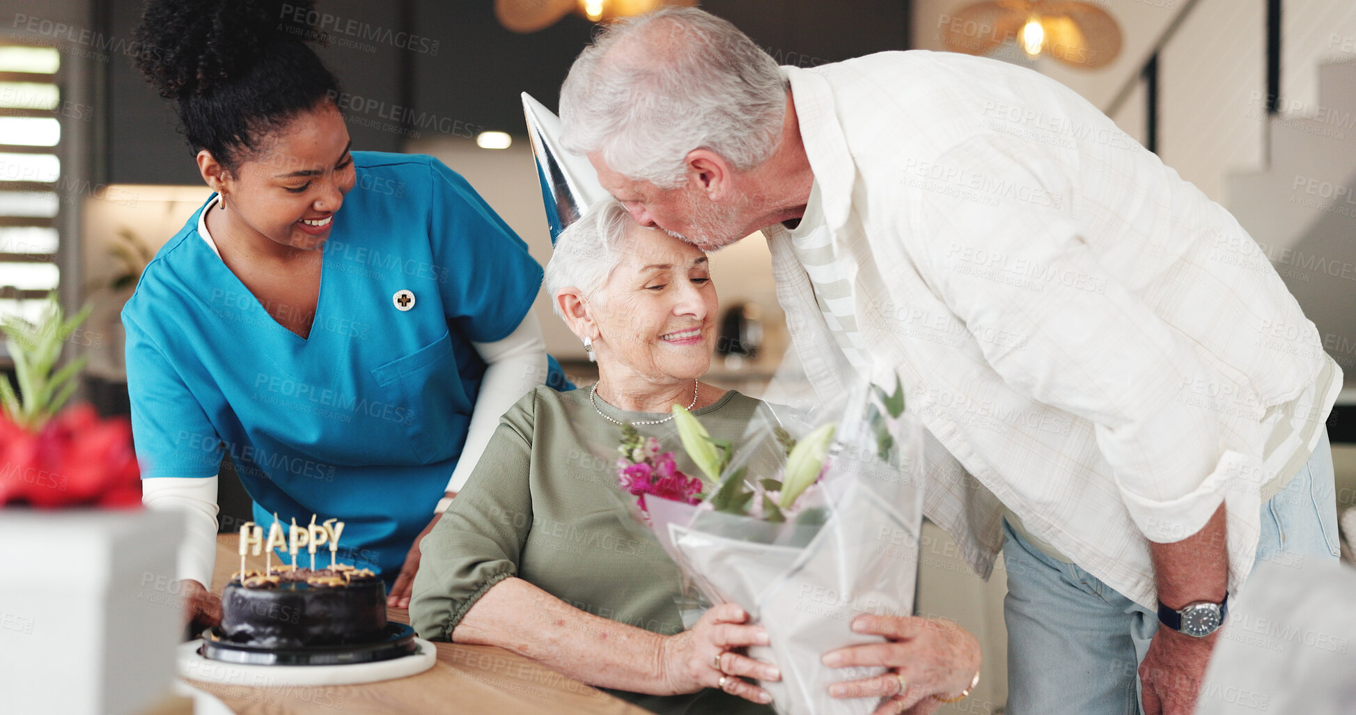 Buy stock photo Senior couple, nurse and kiss with flowers for birthday or anniversary in retirement home together. Elderly, man and woman with caregiver, cake or floral bouquet for love, romance or celebration