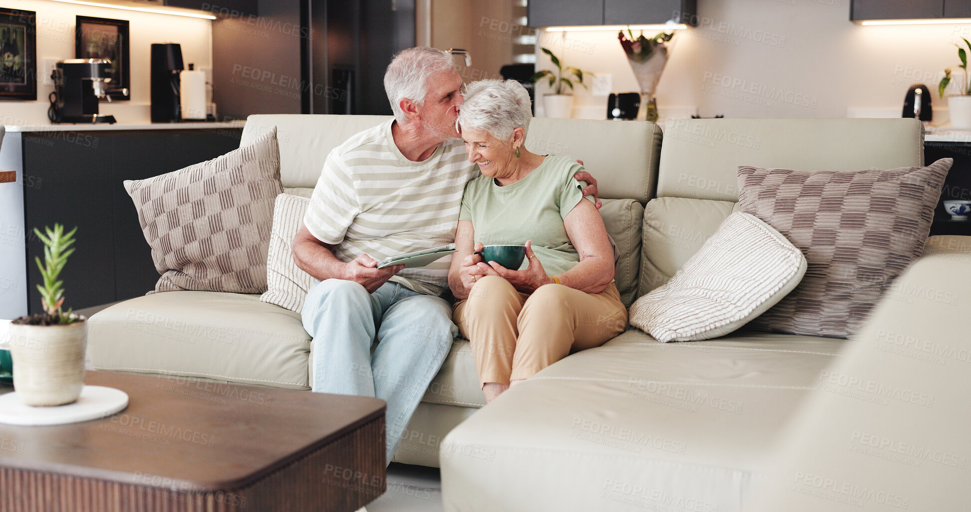 Buy stock photo Coffee, kiss and tablet with old couple on sofa in living room of home together for break. App, bonding and love with funny senior people drinking beverage in apartment for streaming or wellness