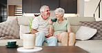 Coffee, laughing and retirement with senior couple on sofa in living room of home together for break. Conversation, bonding and funny with old people drinking beverage in apartment for wellness