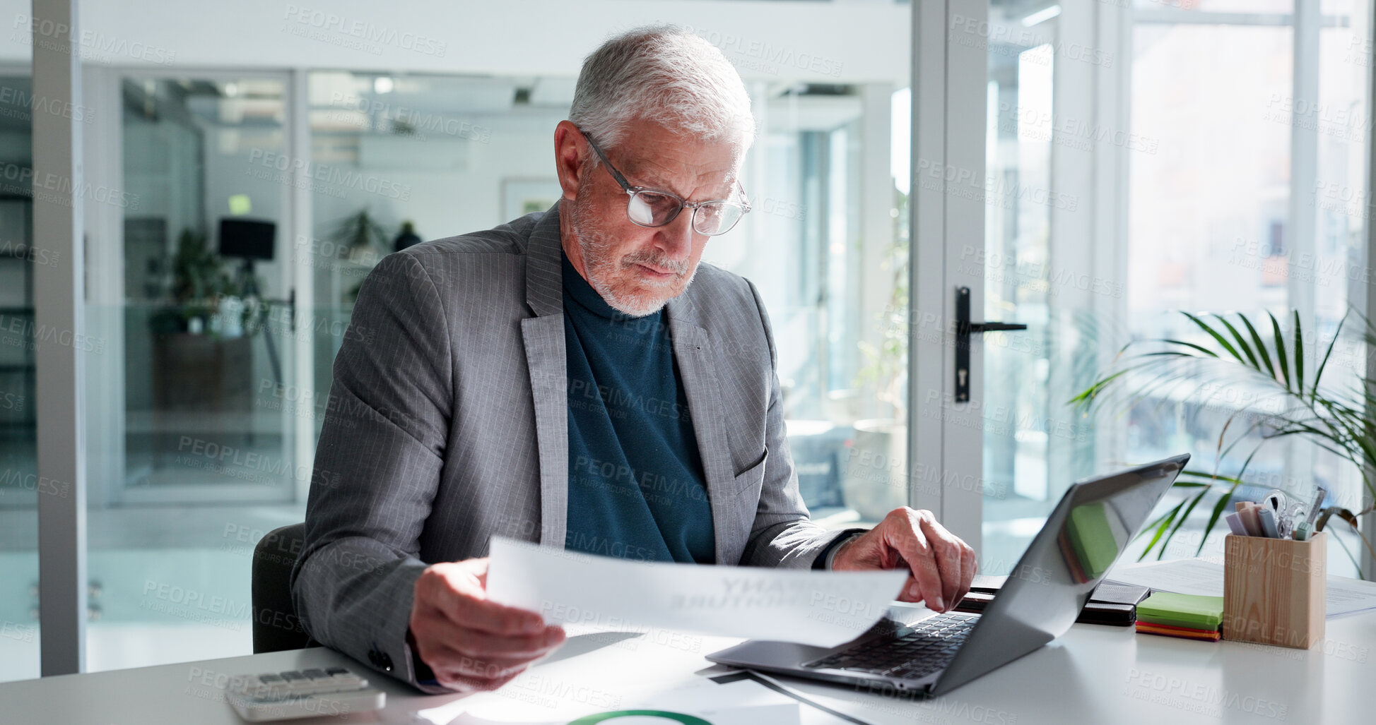 Buy stock photo Man, reading and paperwork in office with laptop for financial statement, budget proposal and report. Mature person, glasses and document with computer for finance management, planning and review.