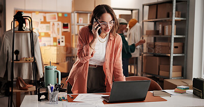 Buy stock photo Woman, designer and phone call with laptop at workshop, smile or dropshipping order at startup. Person, smartphone and computer for talk, happy and contact with creative project for clothes at studio