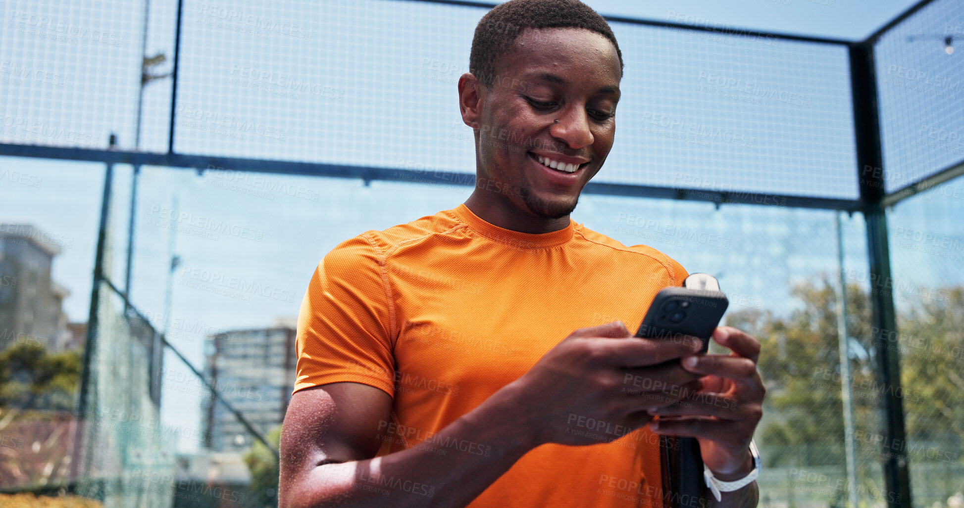 Buy stock photo Man, phone and texting with smile at tennis court, fitness and scroll on break for chat at urban park. African person, low angle and smartphone on mobile app, social media and training at sports club