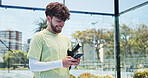 Man, phone and texting with fitness at tennis court padel and smile on break for chat at urban park. Person, athlete and smartphone on mobile app, social media or rest with training at sports club