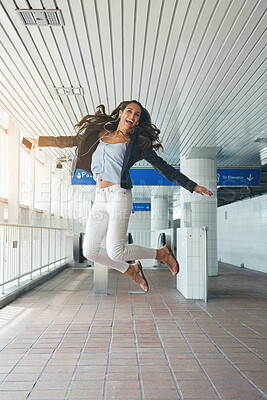 Buy stock photo Happy, woman and jumping with phone at station for travel, streaming podcast and public transport. Female person, energy and mobile with earphones, holiday freedom and listening to music on platform