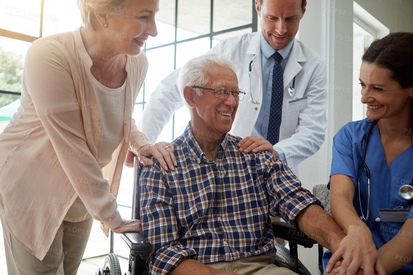 Buy stock photo Laughing, doctor and nurse with senior man in nursing clinic for healthcare discussion. Couple, consultation and elderly male patient in wheelchair with medical employees in retirement facility.
