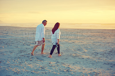 Buy stock photo Sunset, mature couple and walk by sea for vacation trip, connection and bonding together on island. Man, woman and travel at beach with partner for love, tourism and summer holiday with space