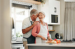Senior couple in kitchen, cooking healthy food together and happy in retirement lifestyle. Elderly woman chopping vegetables with apron, old white man hug wife in home and love nutrition dinner meal