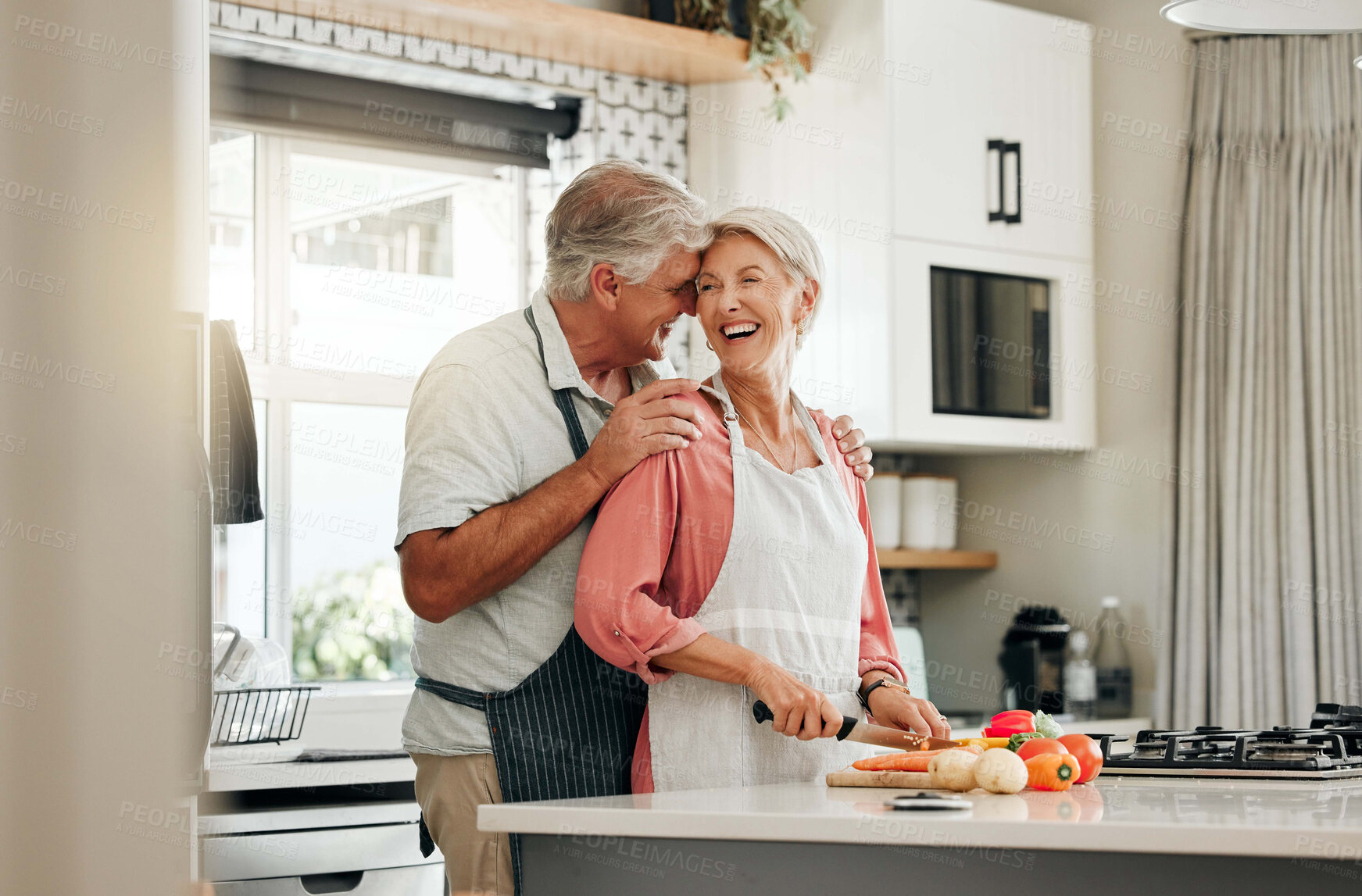 Buy stock photo Senior couple in kitchen, cooking healthy food together and happy in retirement lifestyle. Elderly woman chopping vegetables with apron, old white man hug wife in home and love nutrition dinner meal