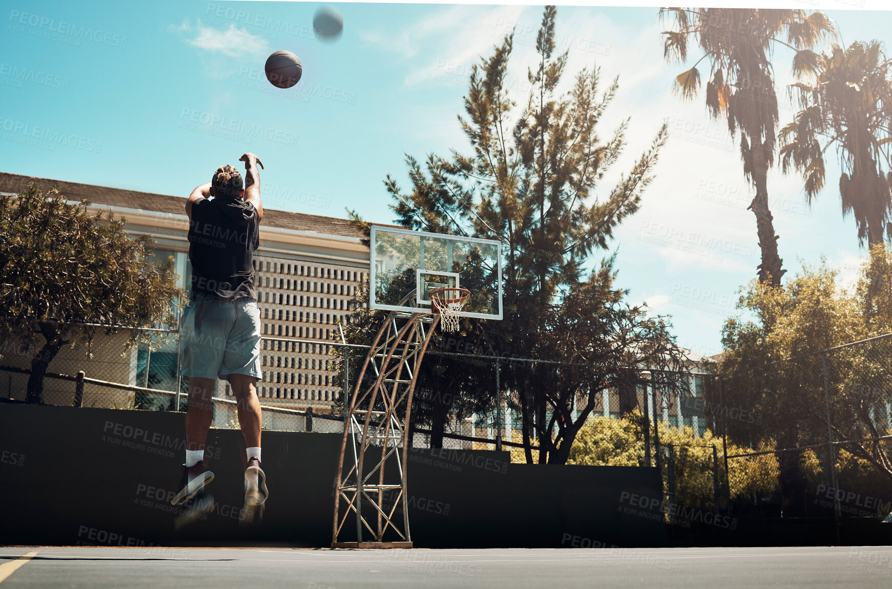 Buy stock photo Basketball, outdoor and a man shooting ball alone on basketball court in Miami summer sun. Fitness, training and health, basketball player jumping to score on court at weekend sports game practice.