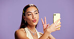 Beauty, peace sign and selfie with influencer woman in studio for product review on social media. App, haircare and pout of playful content creator isolated on purple background for post or update