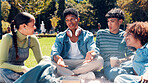 People, students and discussion with book in park for social, education or learning in nature. Group, friends or conversation with novel or story for study, gathering or bonding on grass field
