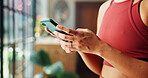 Woman, hands and typing with phone for health tips, workout routine or fitness guide in home. Closeup, female person or texting with mobile smartphone for online app or exercise schedule in house