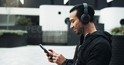 Buy stock photo Fitness, music and phone with man in city for cardio training, running or workout tracking. App, exercise and headphones with athlete or runner typing on mobile for outdoor challenge or sports