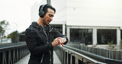 Buy stock photo Headphones, athlete and check watch with running in city for workout progress, performance monitor or app. Runner, man and technology for training, fitness and exercise for podcast or music streaming