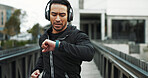 Headphones, man and check smart watch with running in city for workout progress, monitor or app. Runner, athlete and technology for training, fitness and exercise for podcast or music streaming
