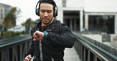 Buy stock photo Headphones, man and check smart watch with running in city for workout progress, monitor or app. Runner, athlete and technology for training, fitness and exercise for podcast or music streaming