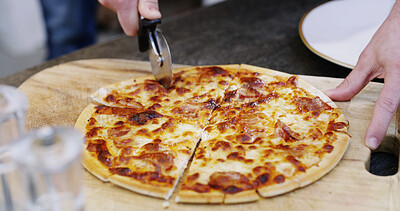 Buy stock photo Person, hands and cutting with pizza on wooden board for dinner, meal or hospitality in home. Closeup, pastry or chef with cheese, food or slices for catering service or italian recipe in kitchen