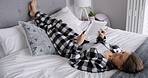 Woman, reading book and lying on bed in home, relax and pyjamas for story, smile or rest with novel. Person, happy and break with literature, fiction and fantasy with language in morning at apartment