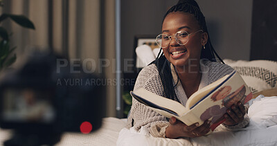 Buy stock photo Woman, influencer and reading book with smile for content creation, camera or literature for children. African person, happy and online tutorial on social media, story or recording on bed at house