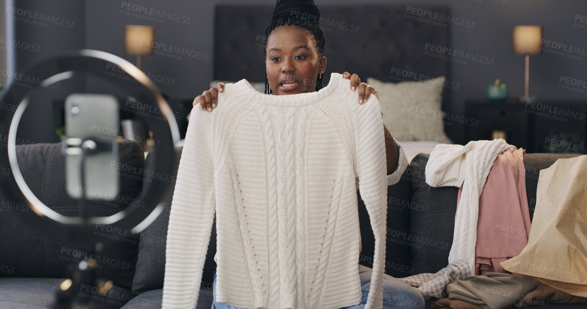 Buy stock photo Content creator, ring light and black woman with clothes in home for talking, product review and opinion. Influencer, bedroom and person with fashion advice, feedback and live streaming for promo