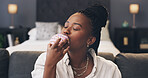 Black woman, hungry and bite donut on sofa in home, sweet snack and junk food on break in bedroom. African person, pastry or eating dessert on couch for sugar craving, cake or cheat meal at apartment