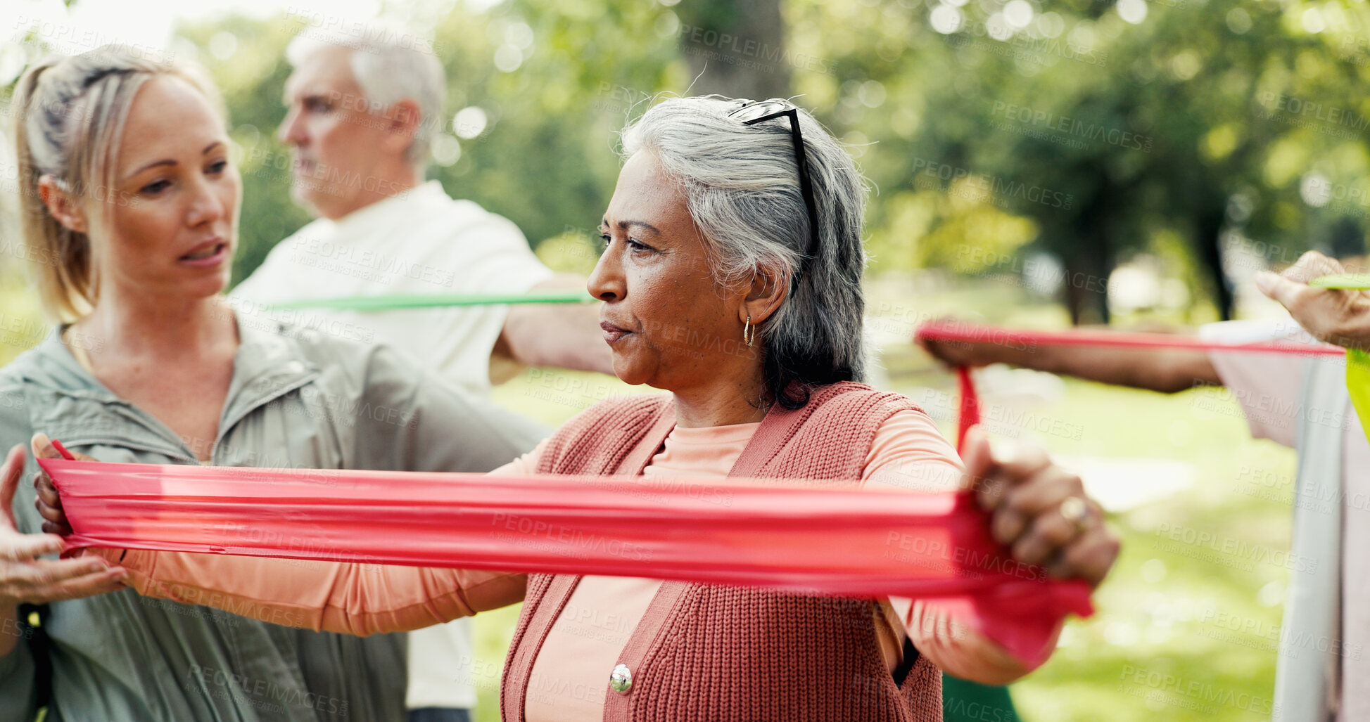 Buy stock photo Resistance band, personal trainer and elderly people in nature for exercise class with stretching. Fitness, equipment and group of senior friends with couch for arm workout for wellness in park.
