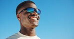 Smile, sunglasses and travel with black man at beach for summer vacation, relax and fashion. Happiness, holiday trip and uv reflection gear with person outdoor for mockup space, tourism and blue sky