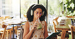 Woman, headphones and tablet in cafe with drink, audiobook or check online university portal. Student, tech for learning platform or reading with matcha or listen to podcast at college cafeteria