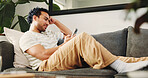 House, smartphone and man on couch, relax and typing with social media, internet and online reading. Apartment, mobile user and Asian person on sofa, cellphone and website info with connection or app