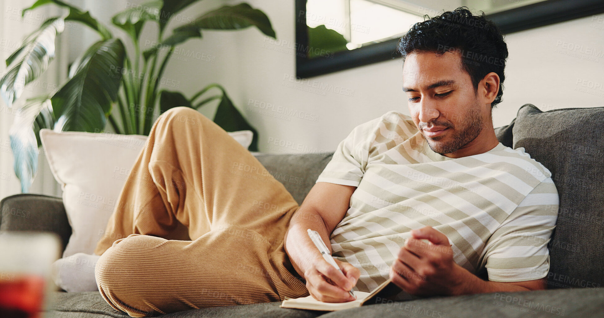 Buy stock photo Man, journal and writing on sofa in home, daily reflection or idea notes to relax for creativity. Person, notebook for planning or sketching with agenda in diary, to do list or goal setting at house