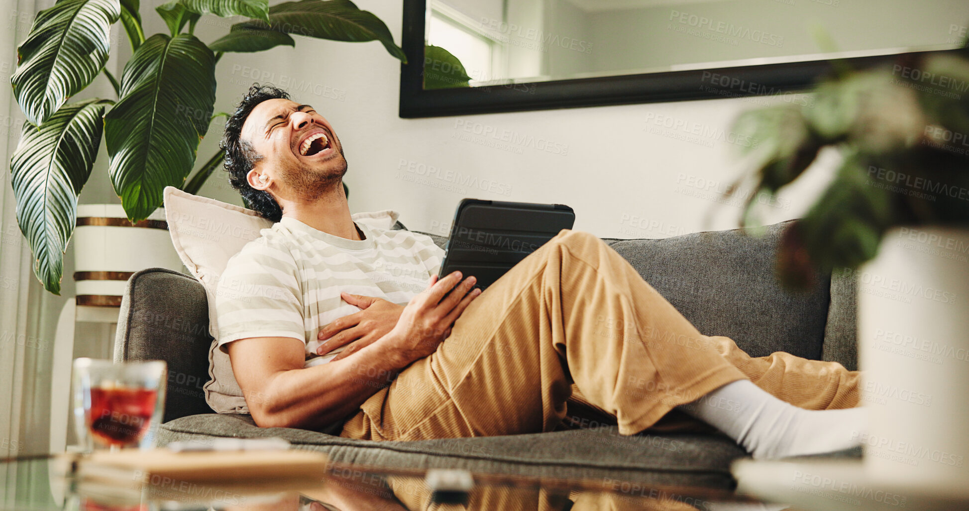 Buy stock photo Man, tablet and laugh on sofa, relax and streaming service for funny movies in living room at home. Person, tech and happy with app, video and comedy film on web, couch or subscription at apartment