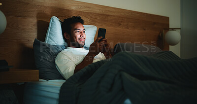 Buy stock photo Phone, relax and man in bed in home at night for texting, social media or connectivity on mobile app. Cellphone, smile and male person with chatting and blog online in bedroom in apartment late.