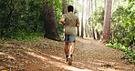 Man, running or exercise with back view in forest for workout, outdoor training or hiking. Active, male person or runner with path on trekking trail for fitness, health or wellness in jungle or woods