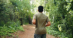 Man, running or exercise with back view in nature for workout, outdoor training or hiking. Active, male person or runner with path on trekking trail for fitness, health or wellness in forest or woods